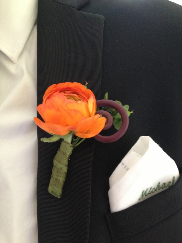 Orange ranunculus with fern curl and green hypericum berry accent by Elegance and Simplicity, Inc.